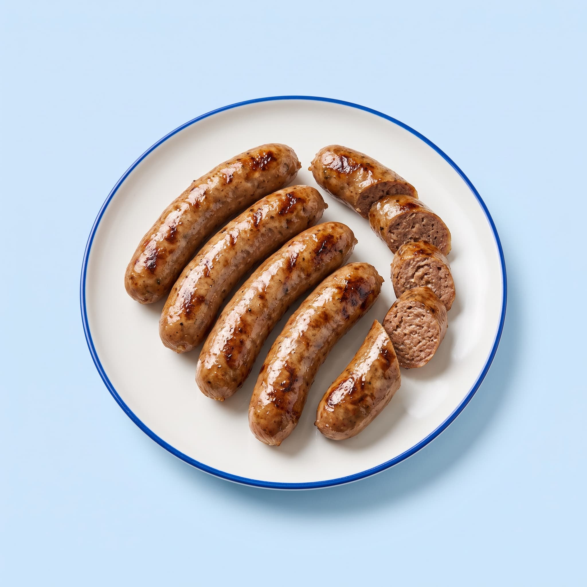 Grilled beef sausages fanned out on a white plate, two of them sliced